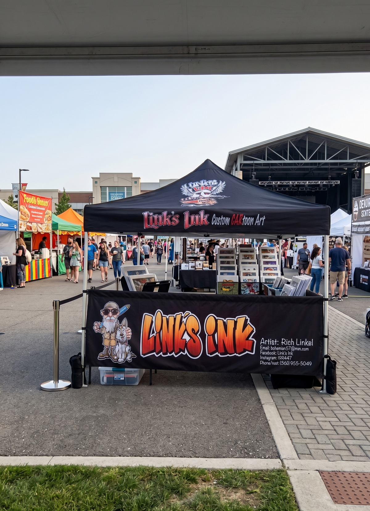 A black pop-up canopy tent and matching front banner for Link's Ink booth at an outdoor market or fair, with people walking in the background under a large structure.