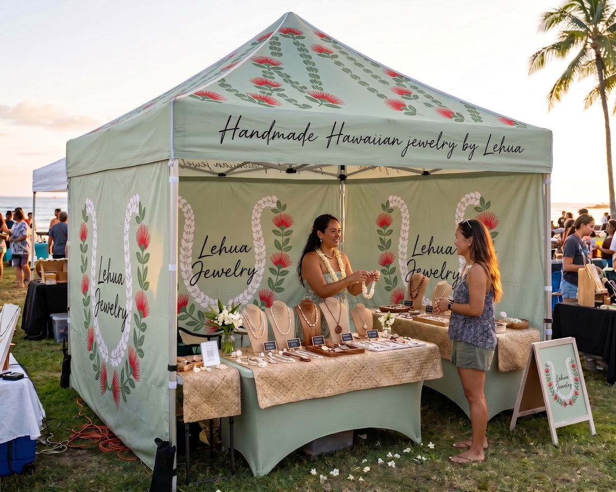 A pop-up event tent at an outdoor market displays jewelry from Lehua Jewelry. The tent is sage green with floral and heart patterns, and the brand name 'Lehua Jewelry' is printed on the front and side.
